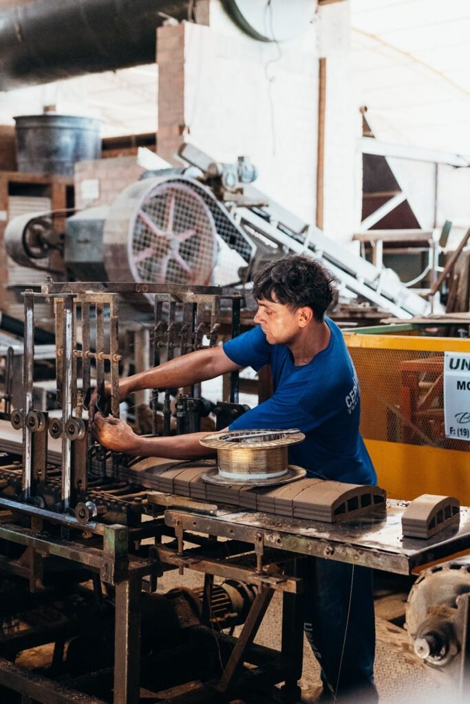 A man in a factory working on machinery for manufacturing industrial products.