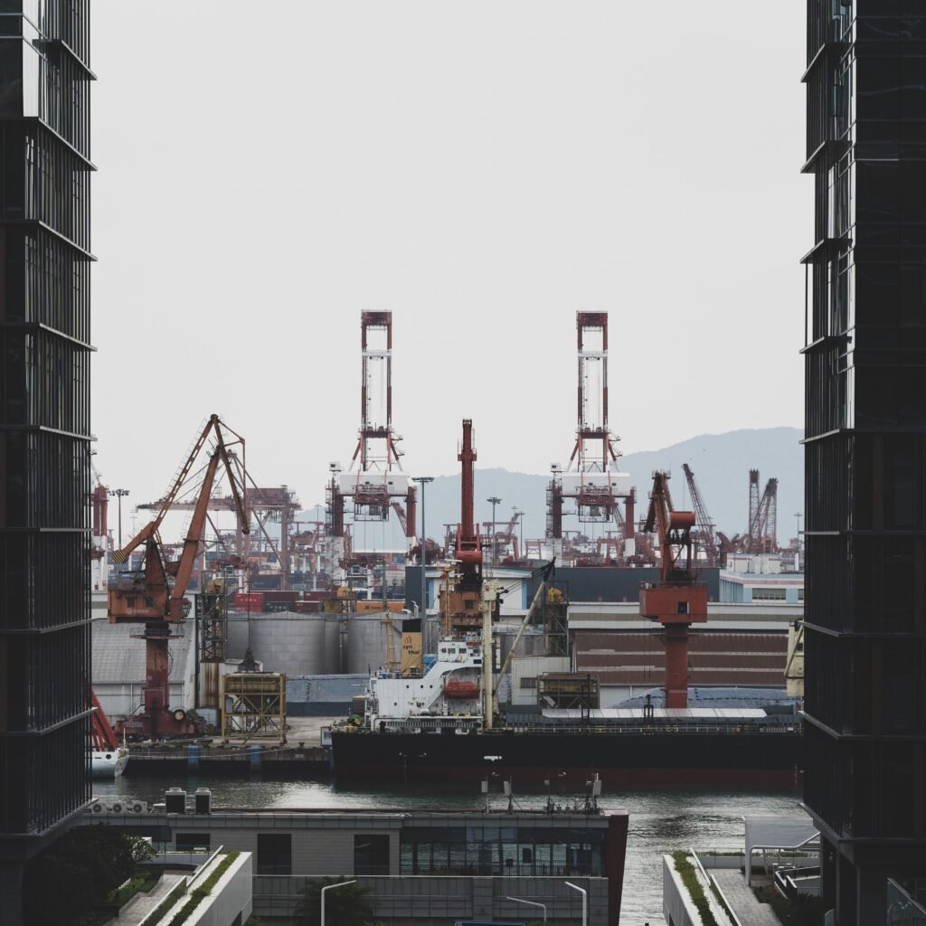 A bustling industrial seaport with cargo ships and cranes, framed by modern architecture.