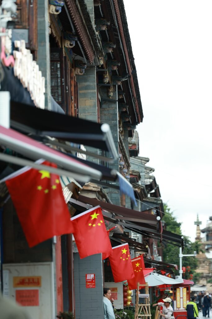 Historic street in China adorned with national flags and traditional Chinese architecture.