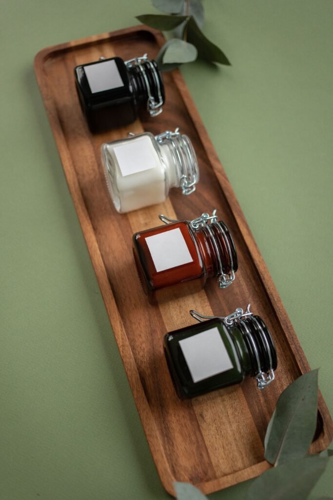 Four colorful glass jars placed on a wooden tray with a green background.