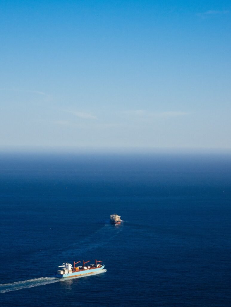 From above of ships sailing on endless ocean under cloudy blue sky during trip in daytime